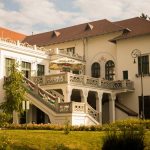 Beautiful historic mansion with intricate architecture and lush garden under a clear sky.