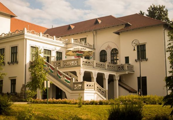 Beautiful historic mansion with intricate architecture and lush garden under a clear sky.
