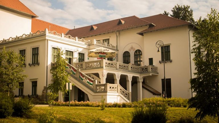 Beautiful historic mansion with intricate architecture and lush garden under a clear sky.